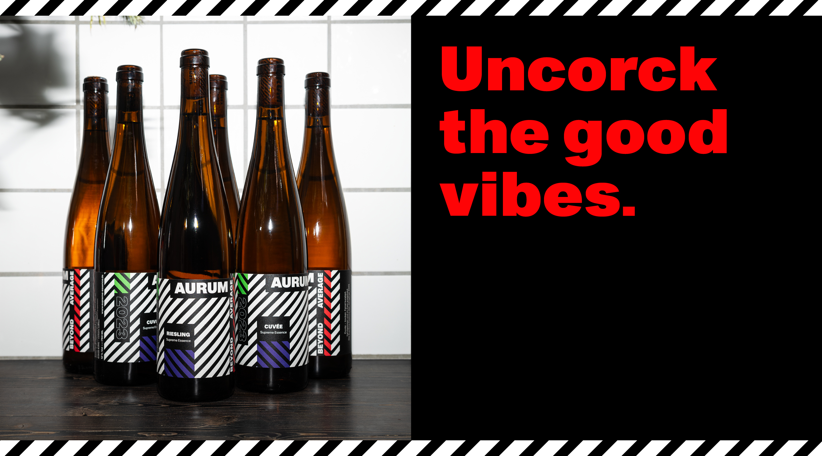 Flaschen des Weins AURUM mit modernem, grafischem Etikettendesign in Schwarz-Weiß mit Farbakzenten. Daneben der Schriftzug 'Uncork the good vibes.' in roter Typografie. Design von Uthmöller und Partner.