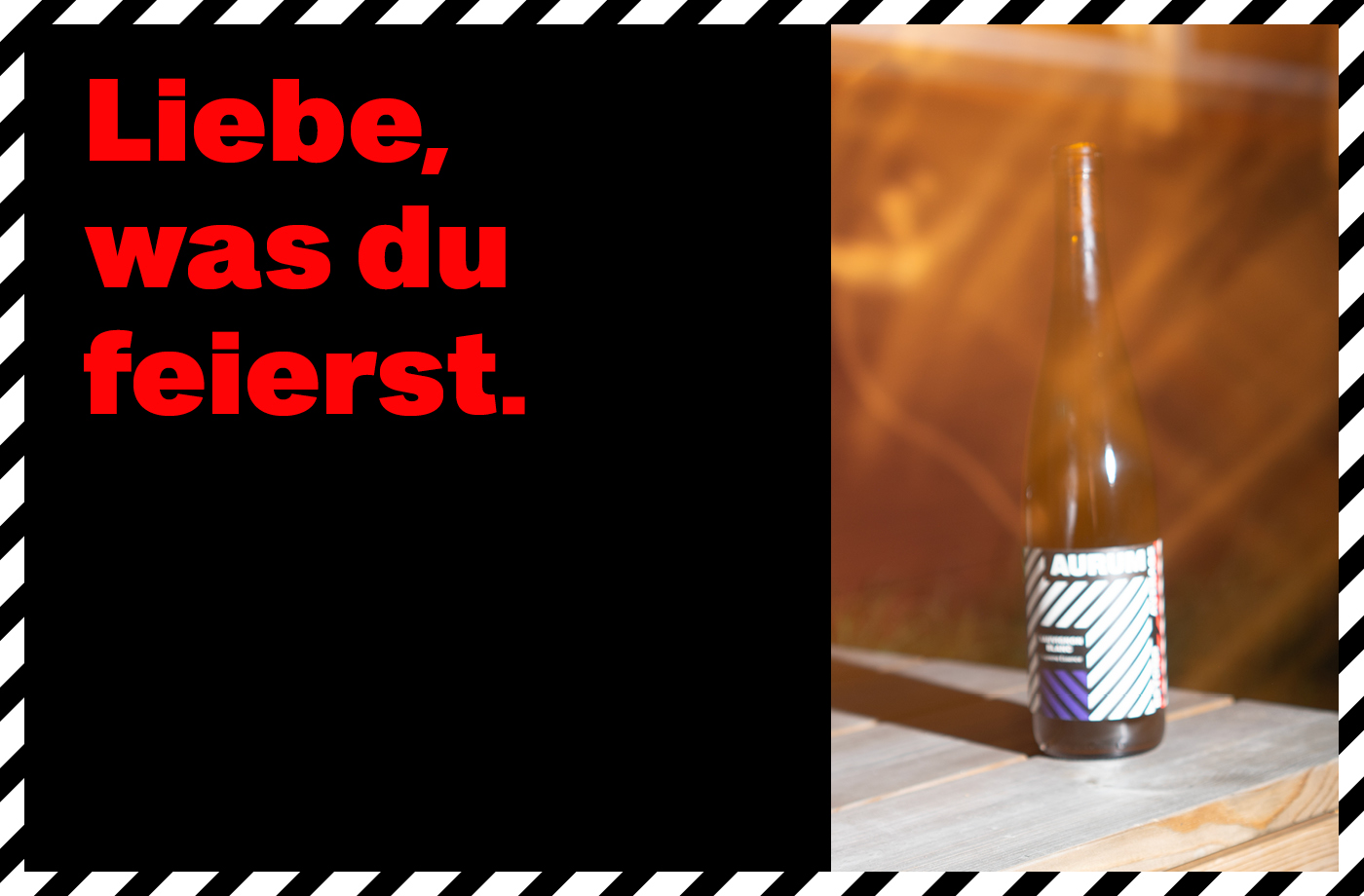 Plakat im markanten Schwarz mit diagonaler Rahmenstruktur. Links der rote Schriftzug: ‚Liebe, was du feierst.‘ Rechts eine Flasche ‚Aurum‘ mit grafisch schwarz-weiß gestreiftem Etikett, inszeniert auf hellem Holz.